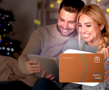 Foto de casal de homem e mulher sorrindo enquanto olham a tela do tablet. A imagem do carto BanriCard Pagamentos est em primeiro plano.